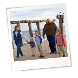 family photo of mom, dad and three sons at the beach